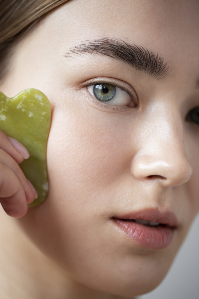 Portrait d'une femme utilisant du guasha pour masser son visage